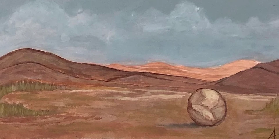 A round boulder in a bare reddish valley beneath grey clouds.